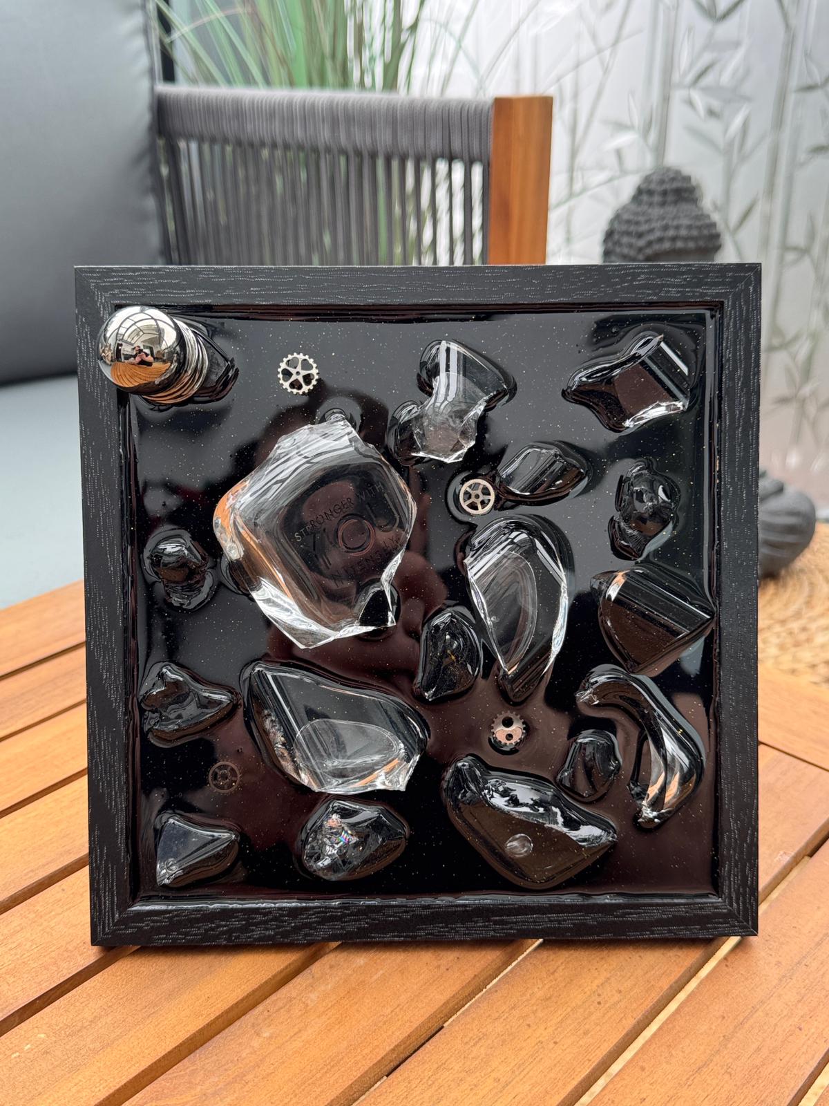 Schwarzer Shadowbox-Rahmen mit glänzenden schwarzen Glas- und Steinelementen sowie kleinen metallischen Details, modern und minimalistisch gestaltet.